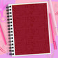 Notebook with red cover featuring black illustrations and '22' on a pink background with stationery items.