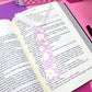 Decorative floral bookmark on an open book with a pink checkered background