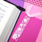 Floral bookmark on a pink surface with an open book