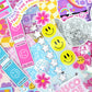 Collection of colorful stickers with smiley faces, flowers, and text on a multicolored background.