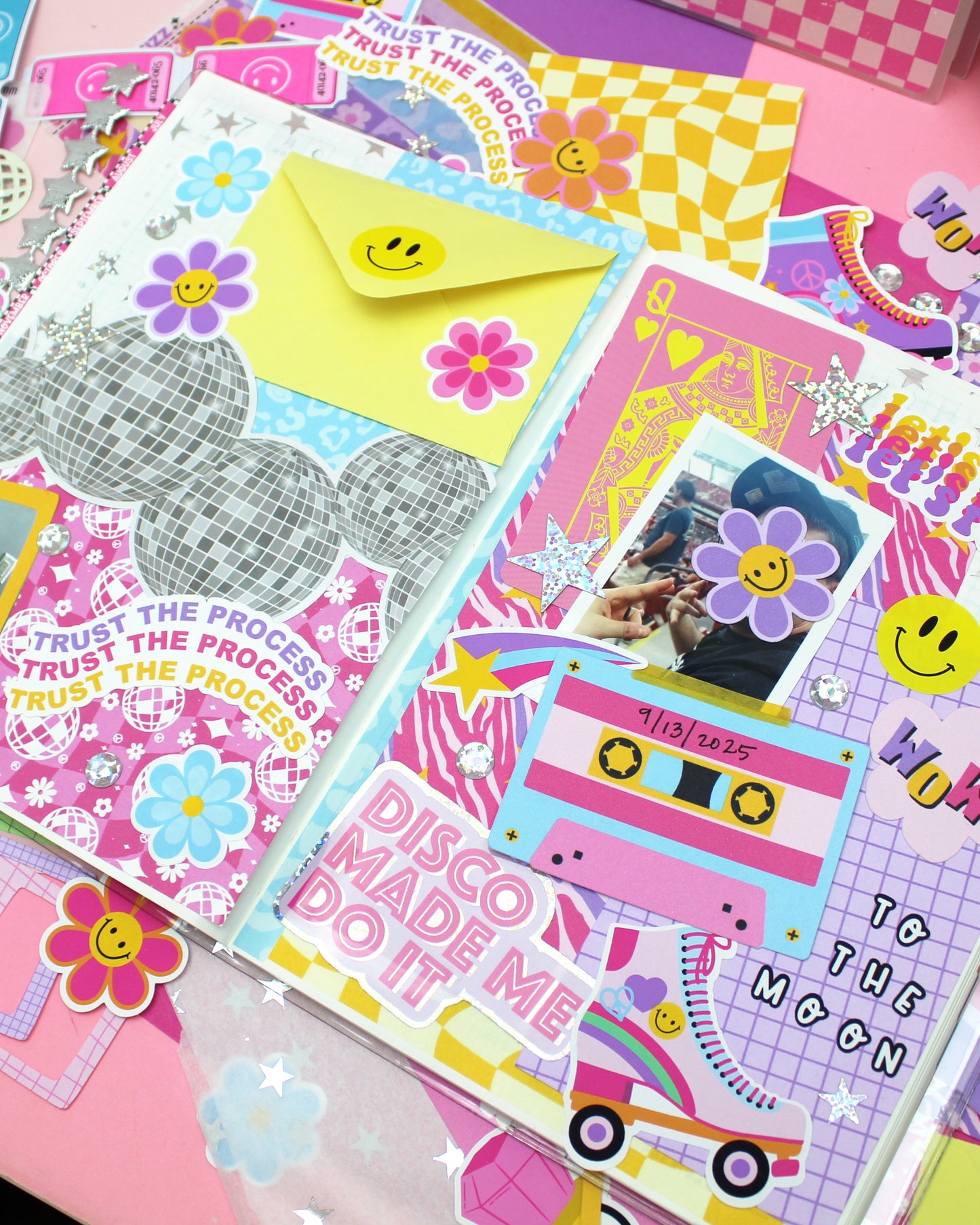 Colorful stationery items including cards, stickers, and envelopes on a pink background.