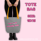 Tote bag with checkered pattern and yellow handles, held by a person on a pink background.
