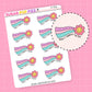 Sticker sheet with rainbow-themed designs and flowers and text that says "made it through the day" on a pink background
