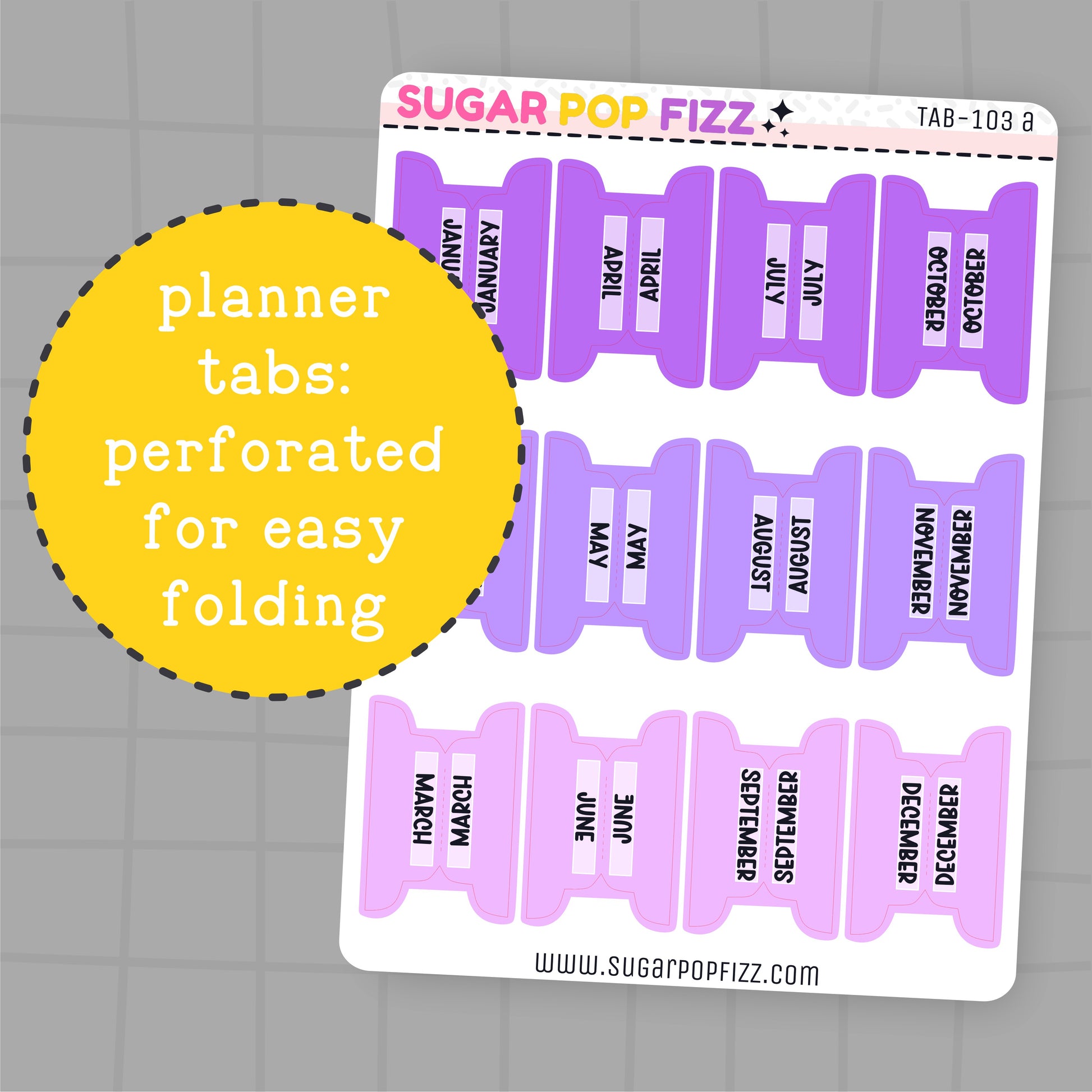 Purple planner tabs with months printed on them, perforated for easy folding, on a gray grid background.